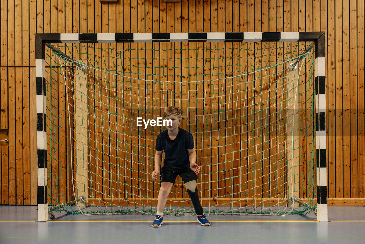 Focused male goalie with disability standing in front of net at sports court