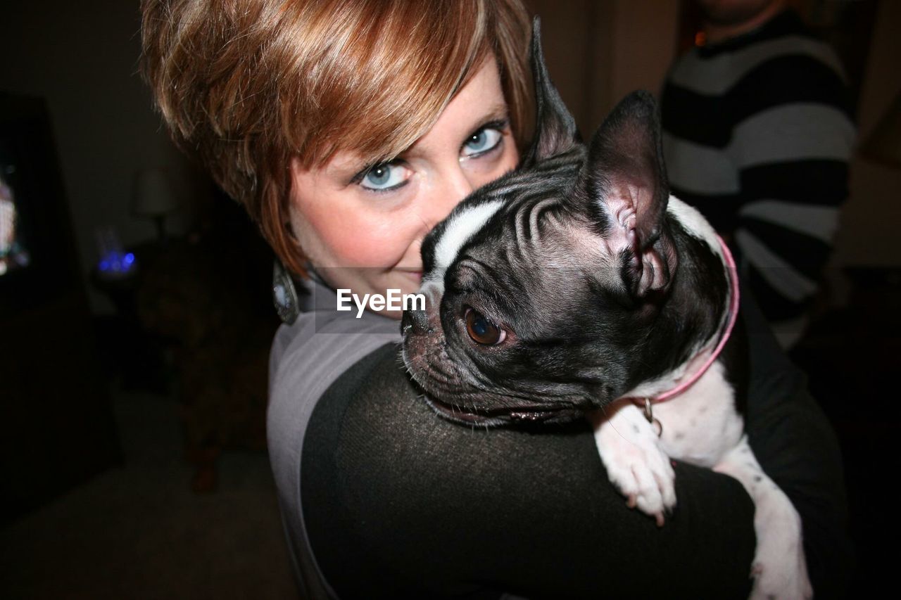 Portrait of mature woman embracing french bulldog at home