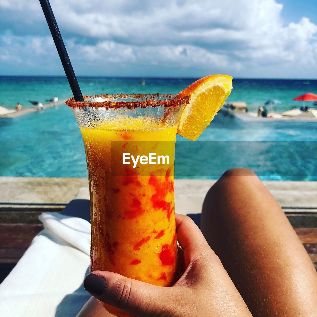 Midsection of woman holding drink against sea