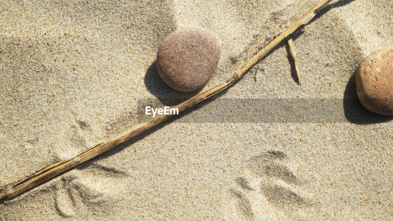 HIGH ANGLE VIEW OF PEBBLES ON BEACH