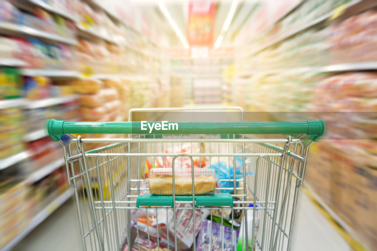 Close-up of shopping cart at aisle in supermarket