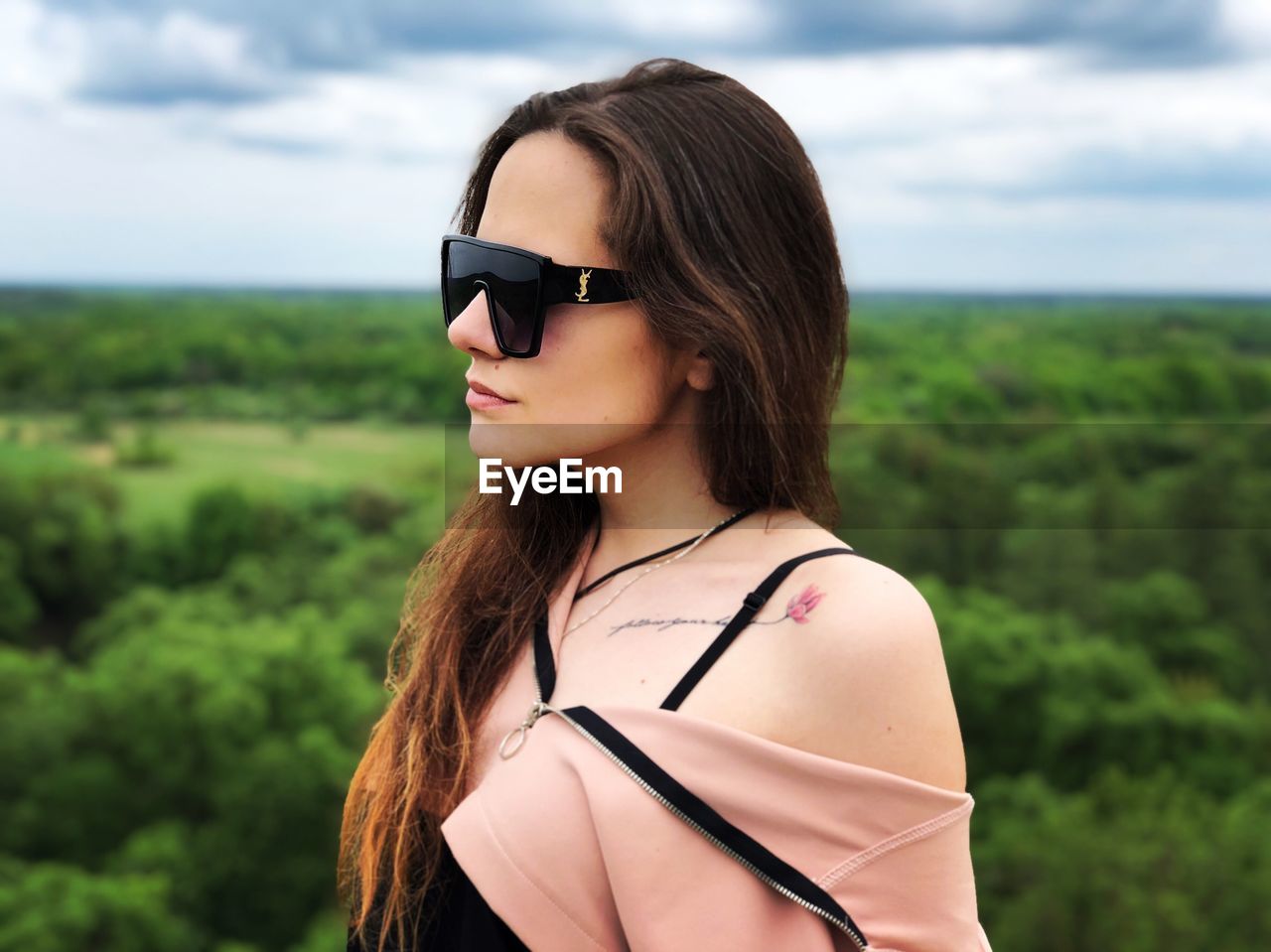 PORTRAIT OF YOUNG WOMAN WEARING SUNGLASSES AGAINST SKY