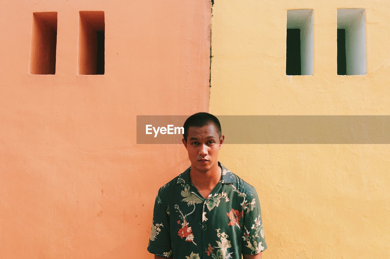 Portrait of young man standing against wall