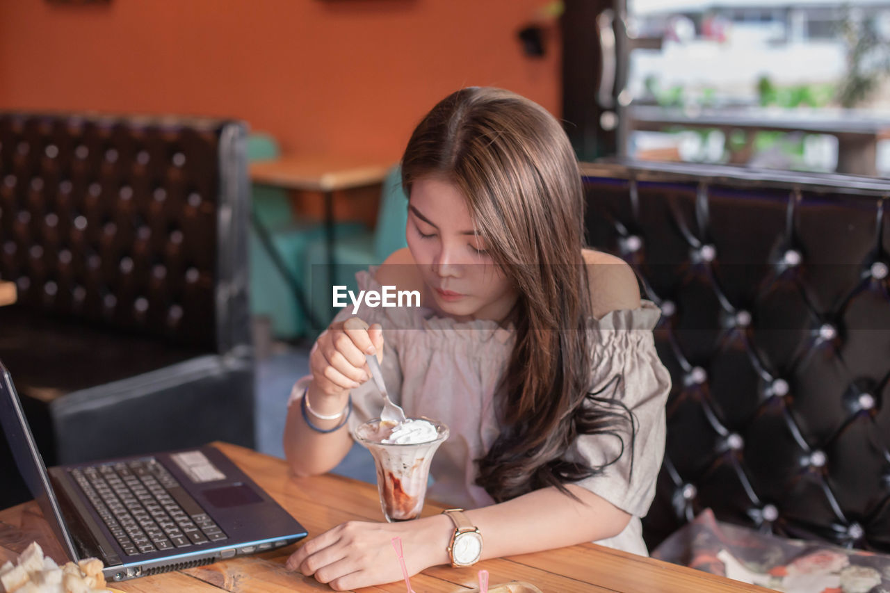 YOUNG WOMAN USING MOBILE PHONE AT TABLE