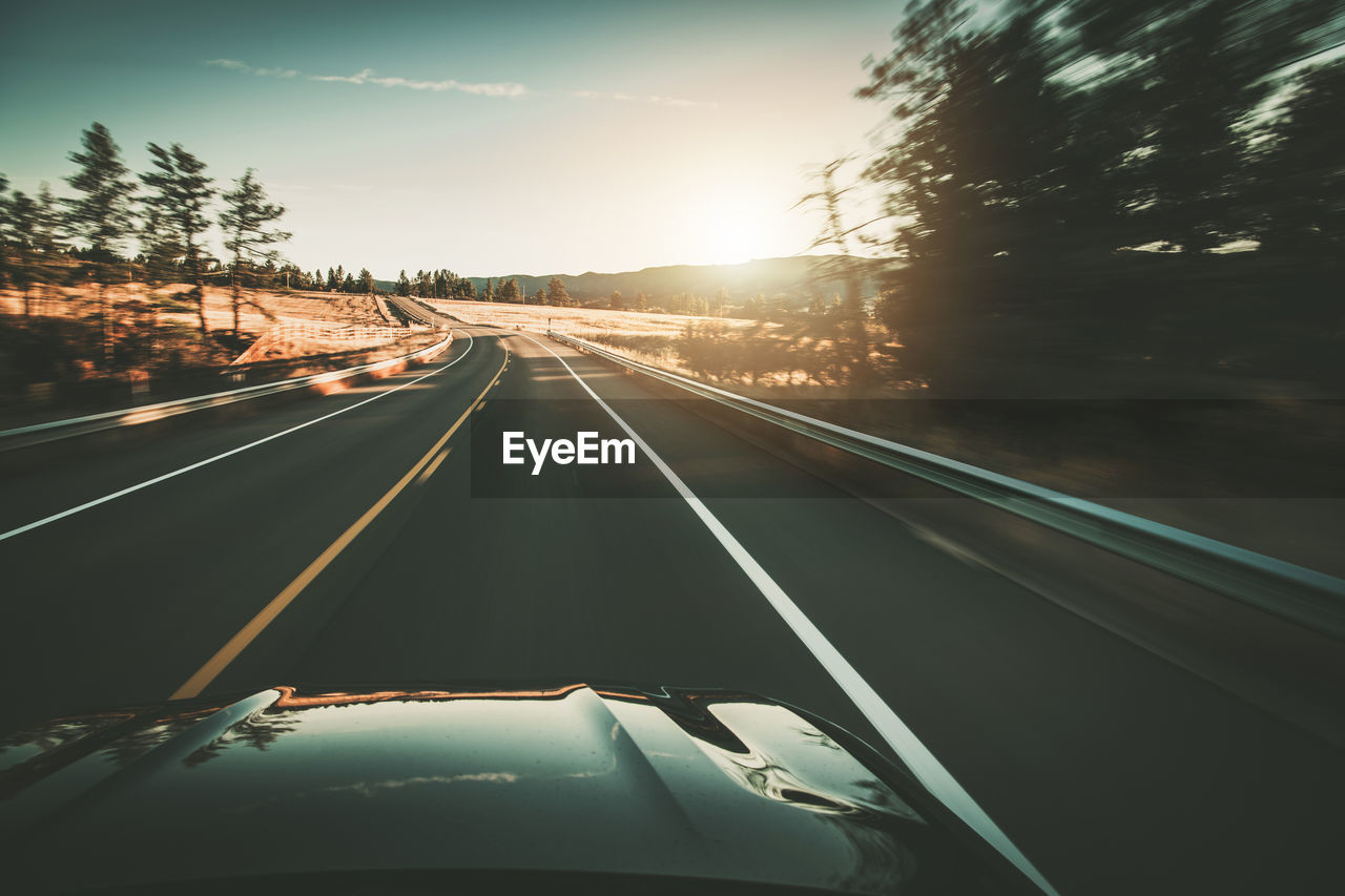 light trails on highway against sky during sunset