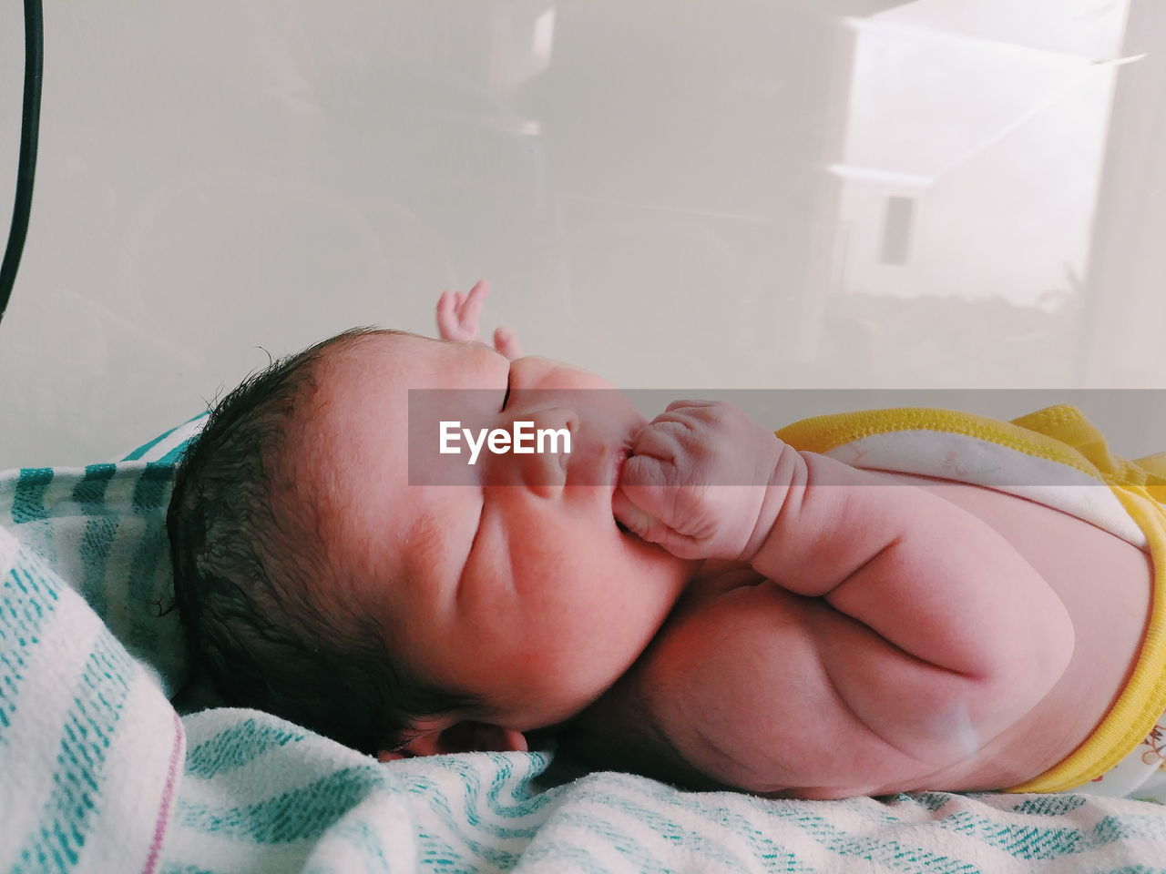 Close-up of cute newborn sleeping on bed at home