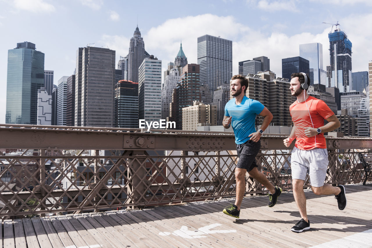 Usa, new york city, two men running on brooklyn brige