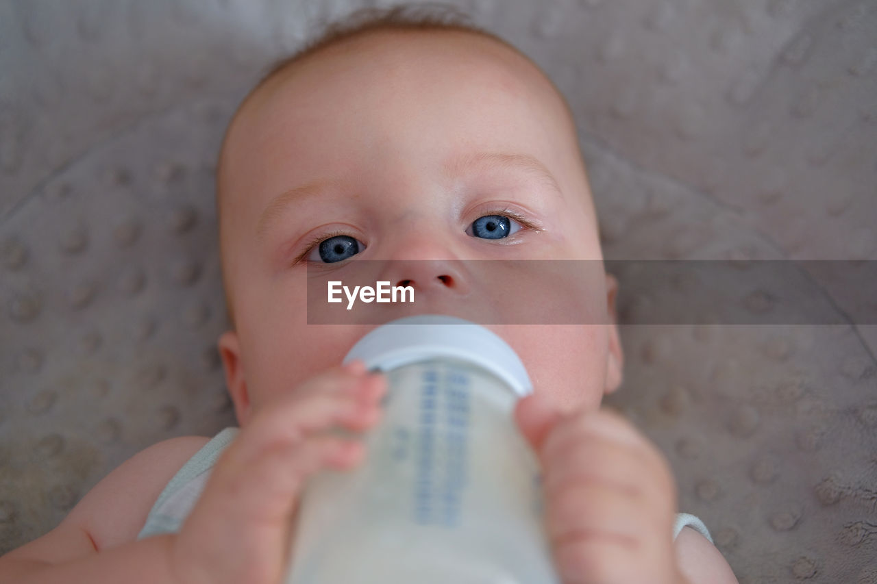 Close-up of a cute baby holding a milk bottle