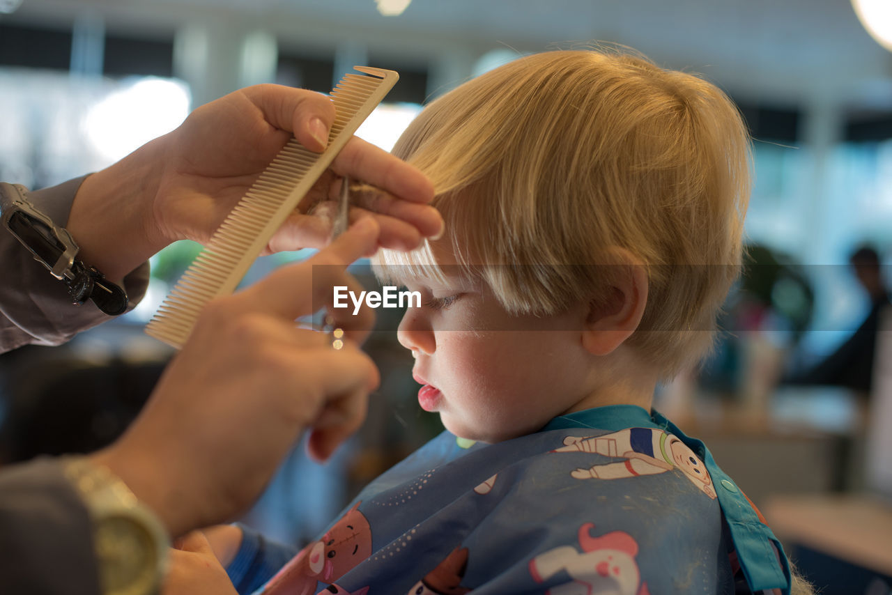 Cropped image of barber cutting boy hair