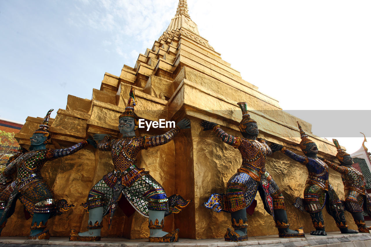 Low angle view of golden statues by pagoda