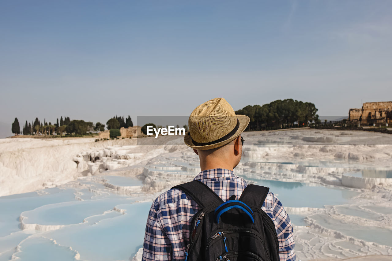 Young male tourist in straw hat looking to the natural travertine pools  in pamukkale, turkey