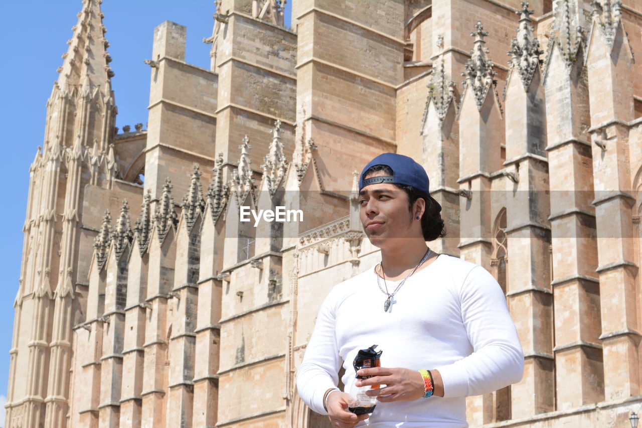 Low angle view of man standing against palma cathedral on sunny day