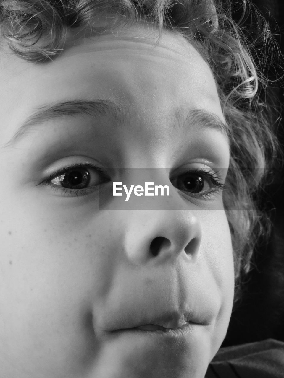 Close-up of boy looking away against black background