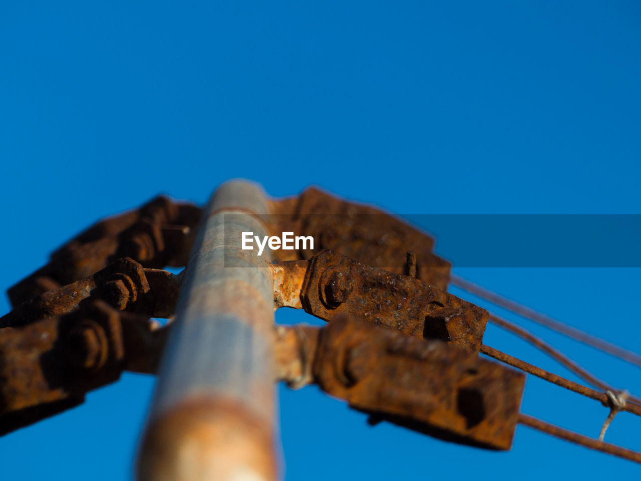 Low angle view of rusty metal against blue sky