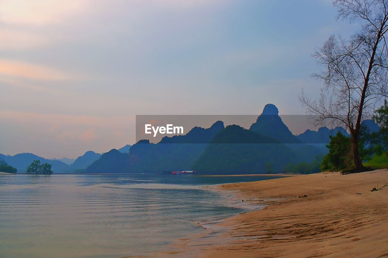 SCENIC VIEW OF BEACH AGAINST SKY AT SUNSET