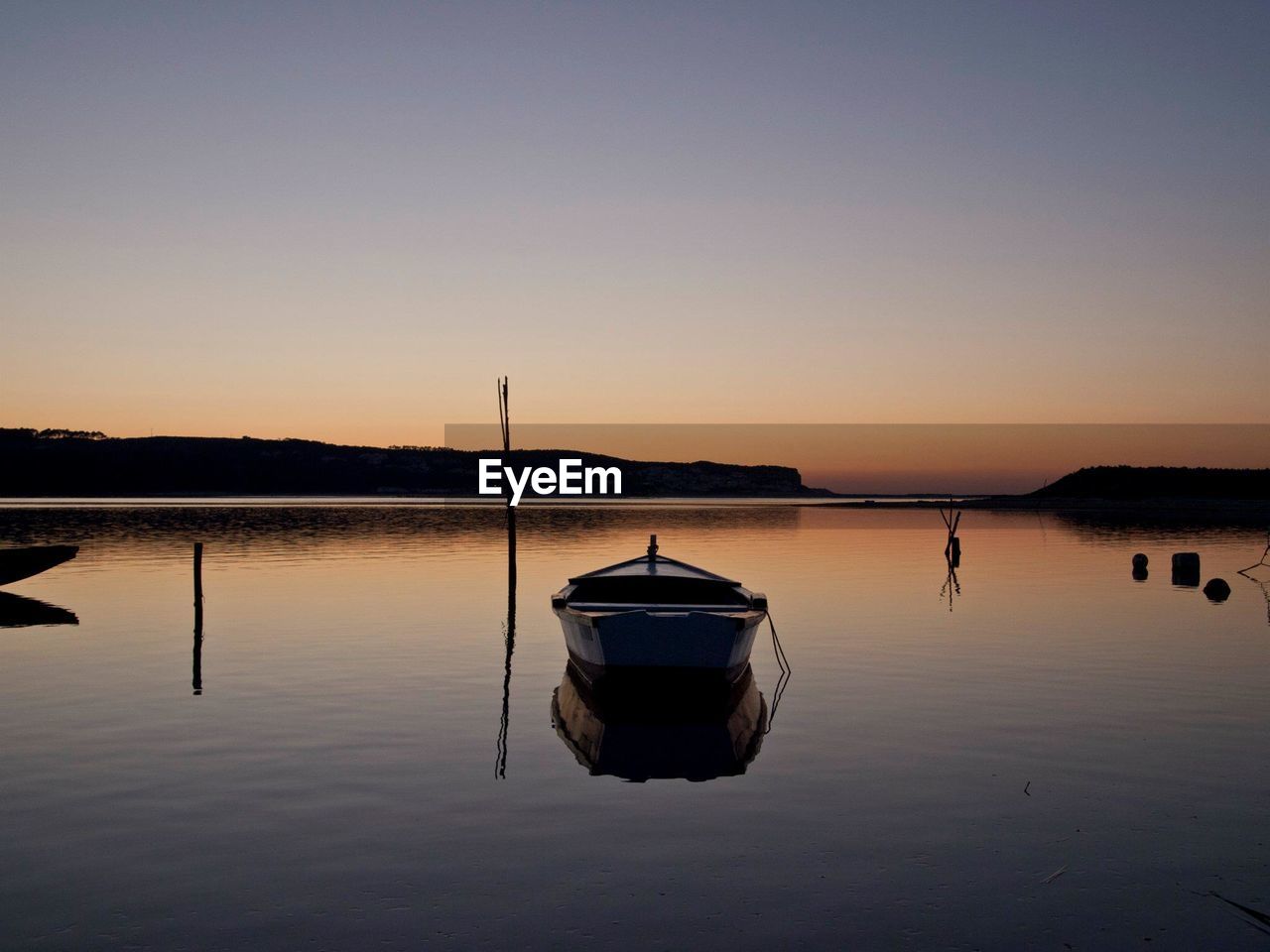 Boat on lake against sky during sunset