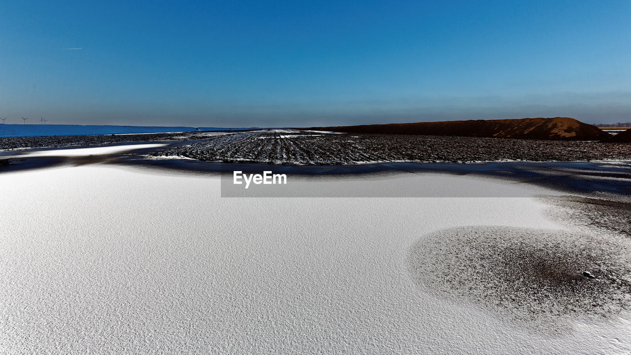 Scenic view of beach against clear blue sky