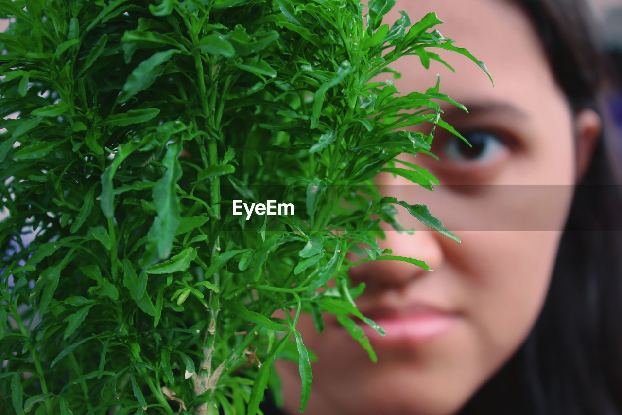 Close-up portrait of young woman by plants