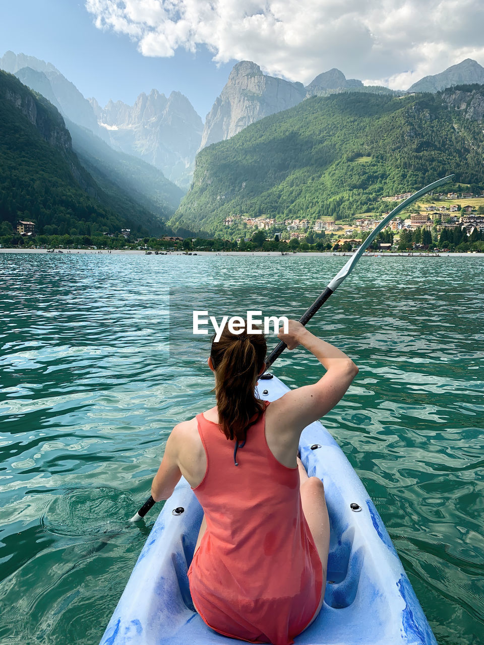 Young woman paddling on kayak at molveno lake, italy.