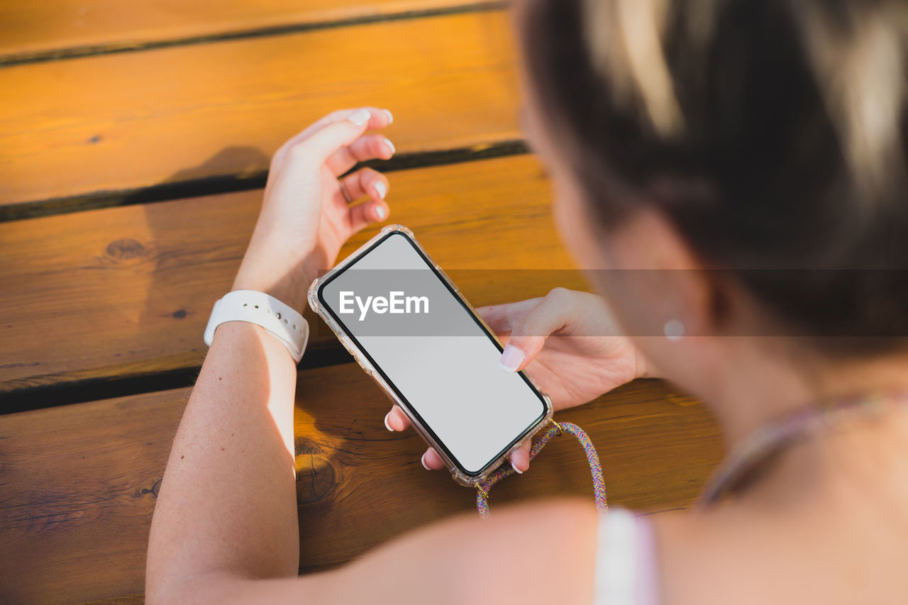 MIDSECTION OF WOMAN USING SMART PHONE OUTDOORS