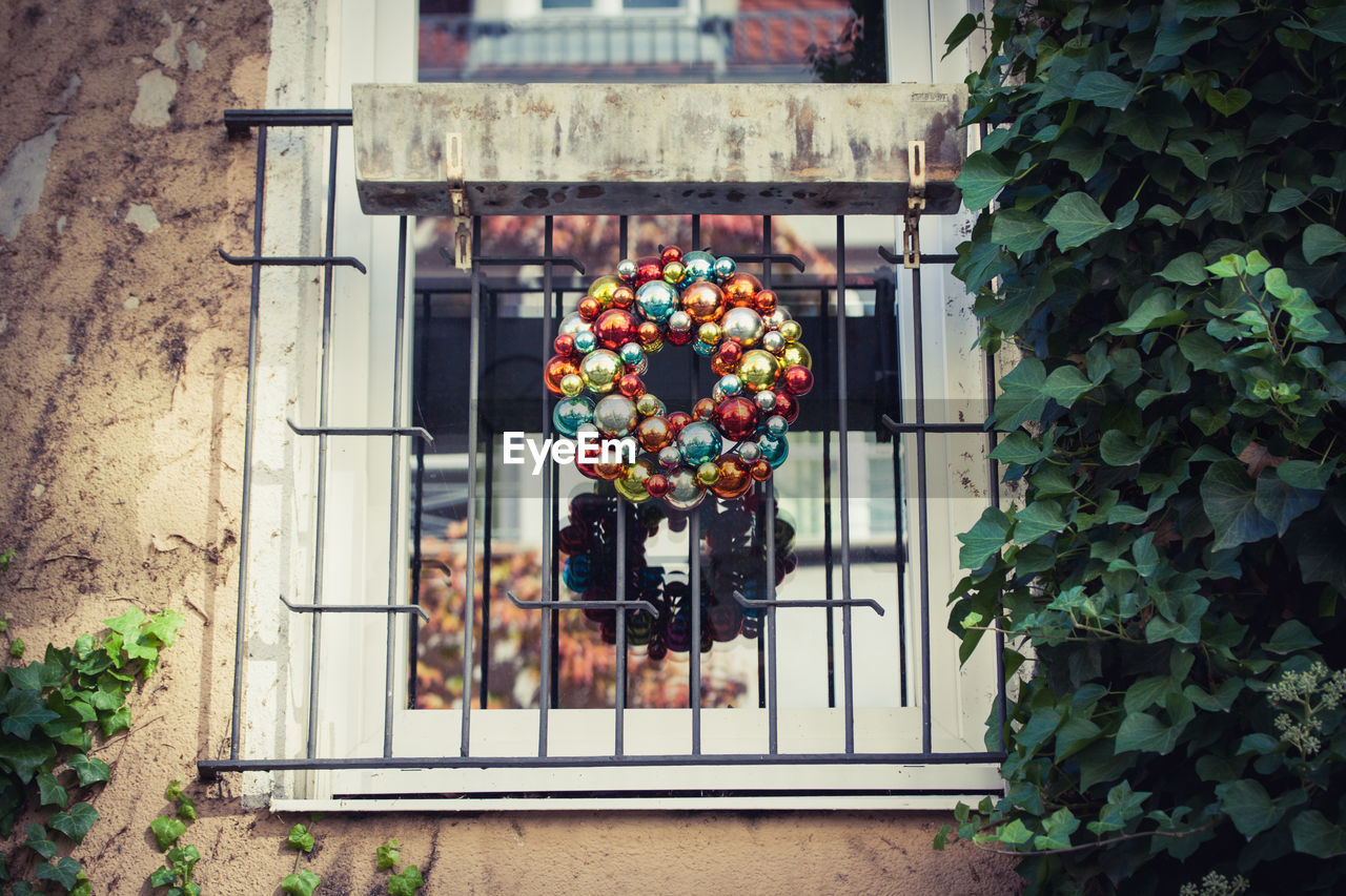 Multi colored wreath of christmas baubles on window 