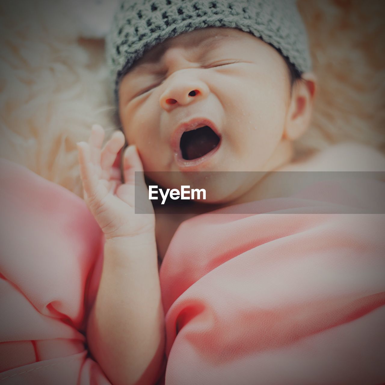 Close-up of cute baby girl yawning on bed
