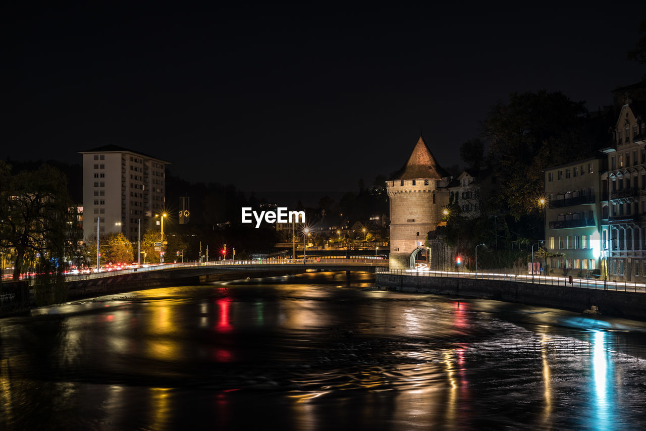 View of illuminated bridge over river in city at night