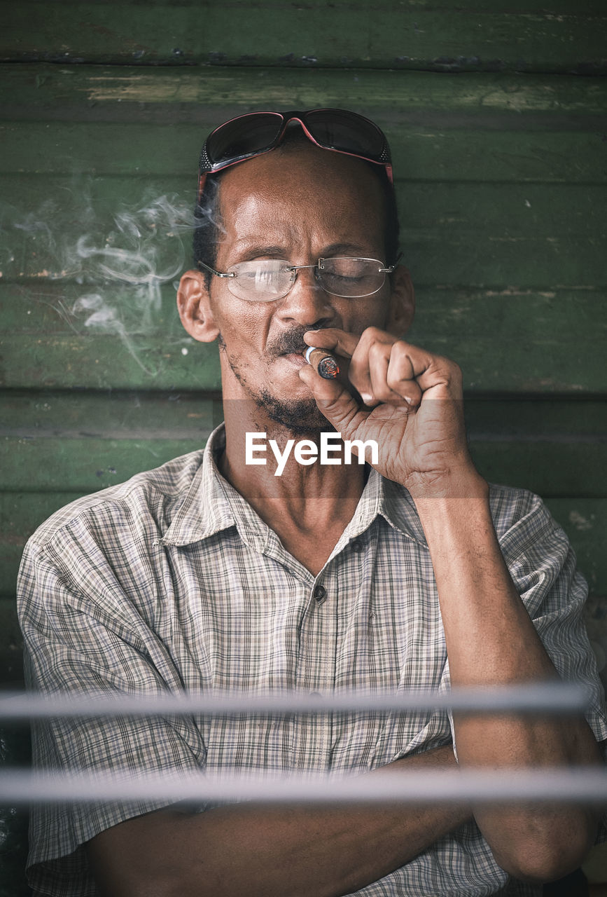 PORTRAIT OF MAN SMOKING CIGARETTE AT HOME