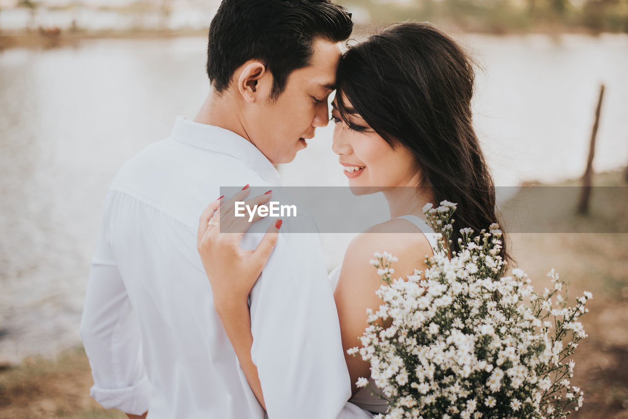 Young couple with white flowers romancing outdoors