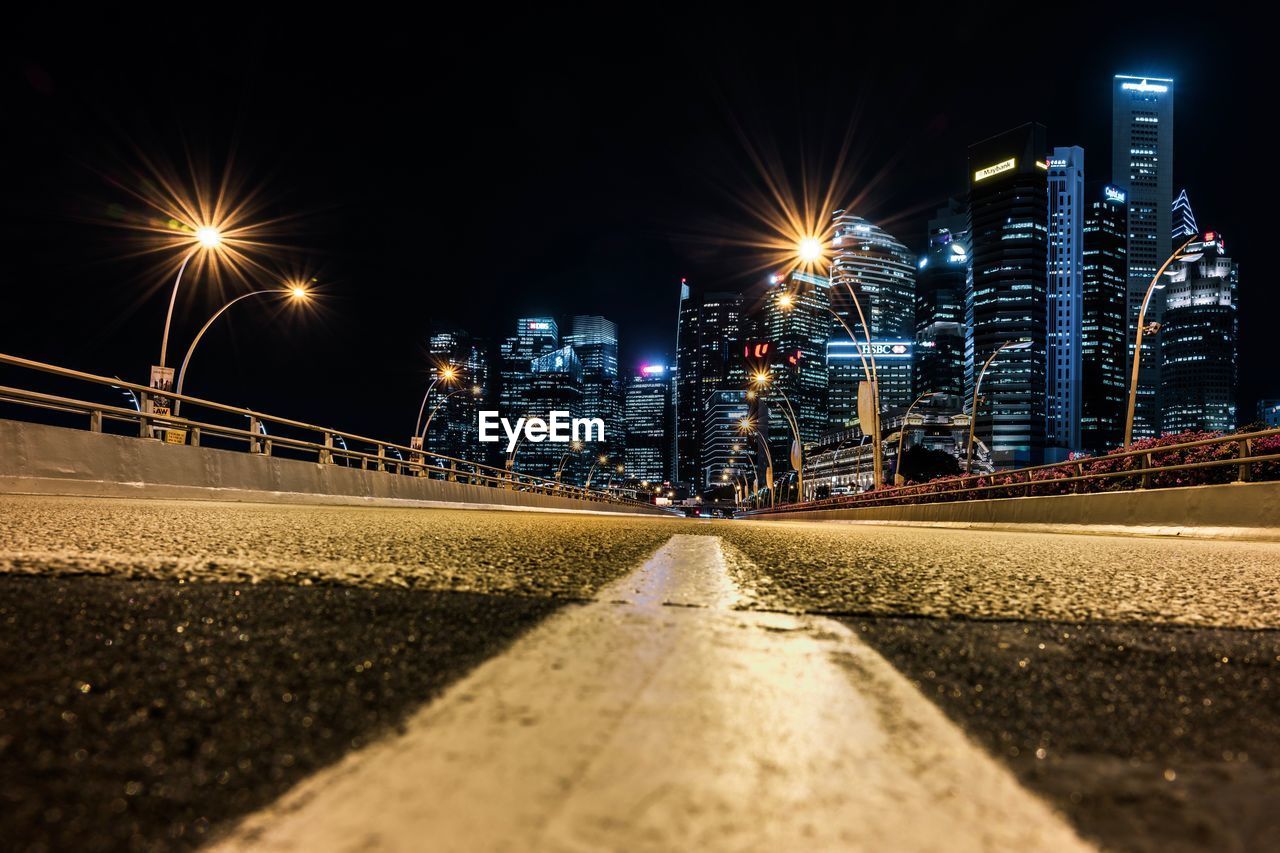 Surface level of road by buildings against sky at night