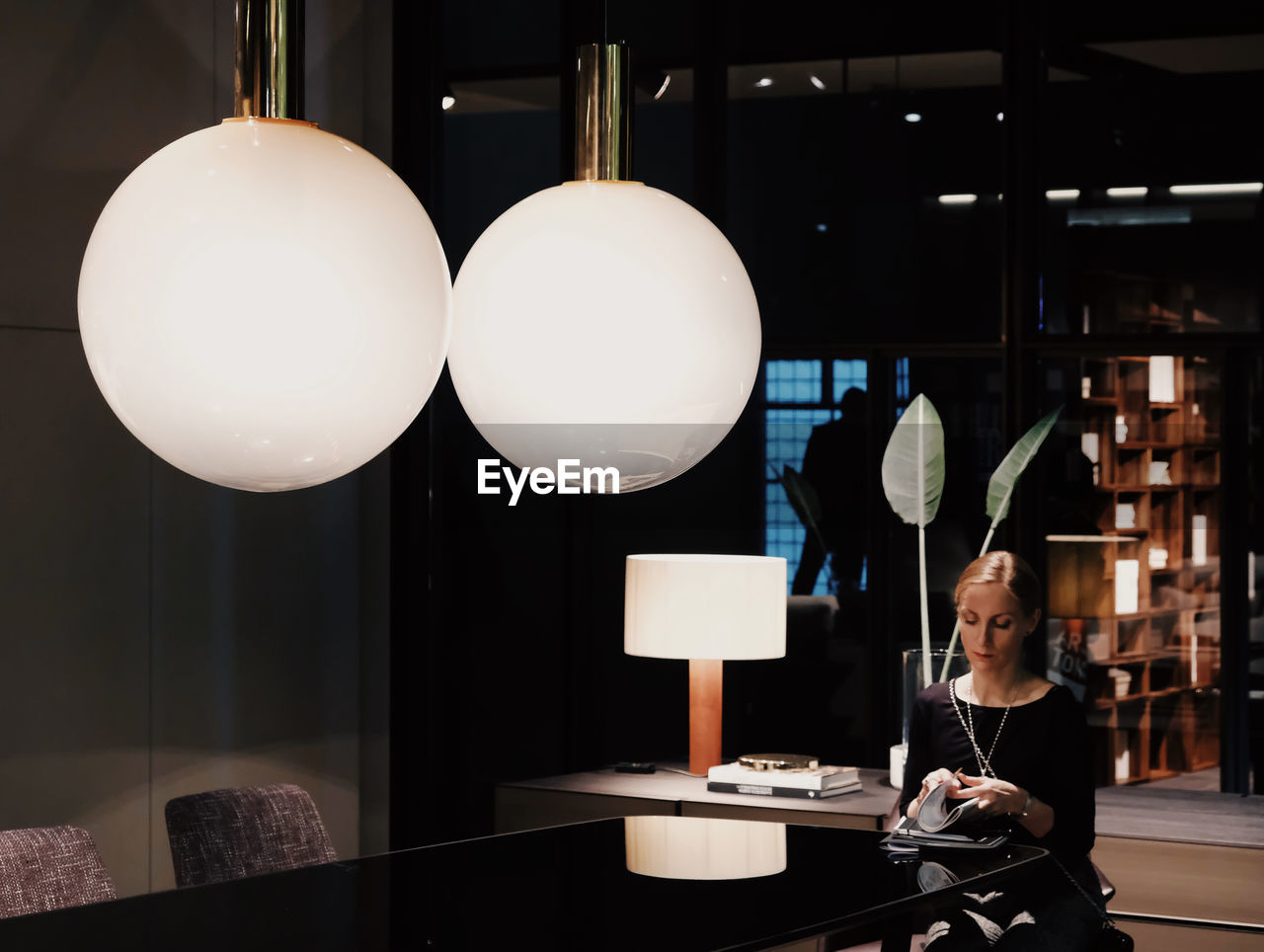 FULL LENGTH OF MAN SITTING ON TABLE AT ILLUMINATED LAMP