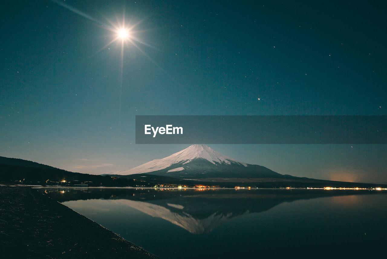 Mount fuji reflecting in lake against sky at night