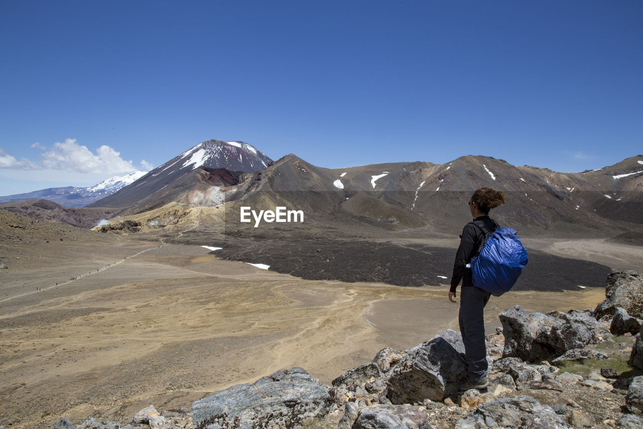 Male hiker looking at scenic landscape of a lava field and a volcano