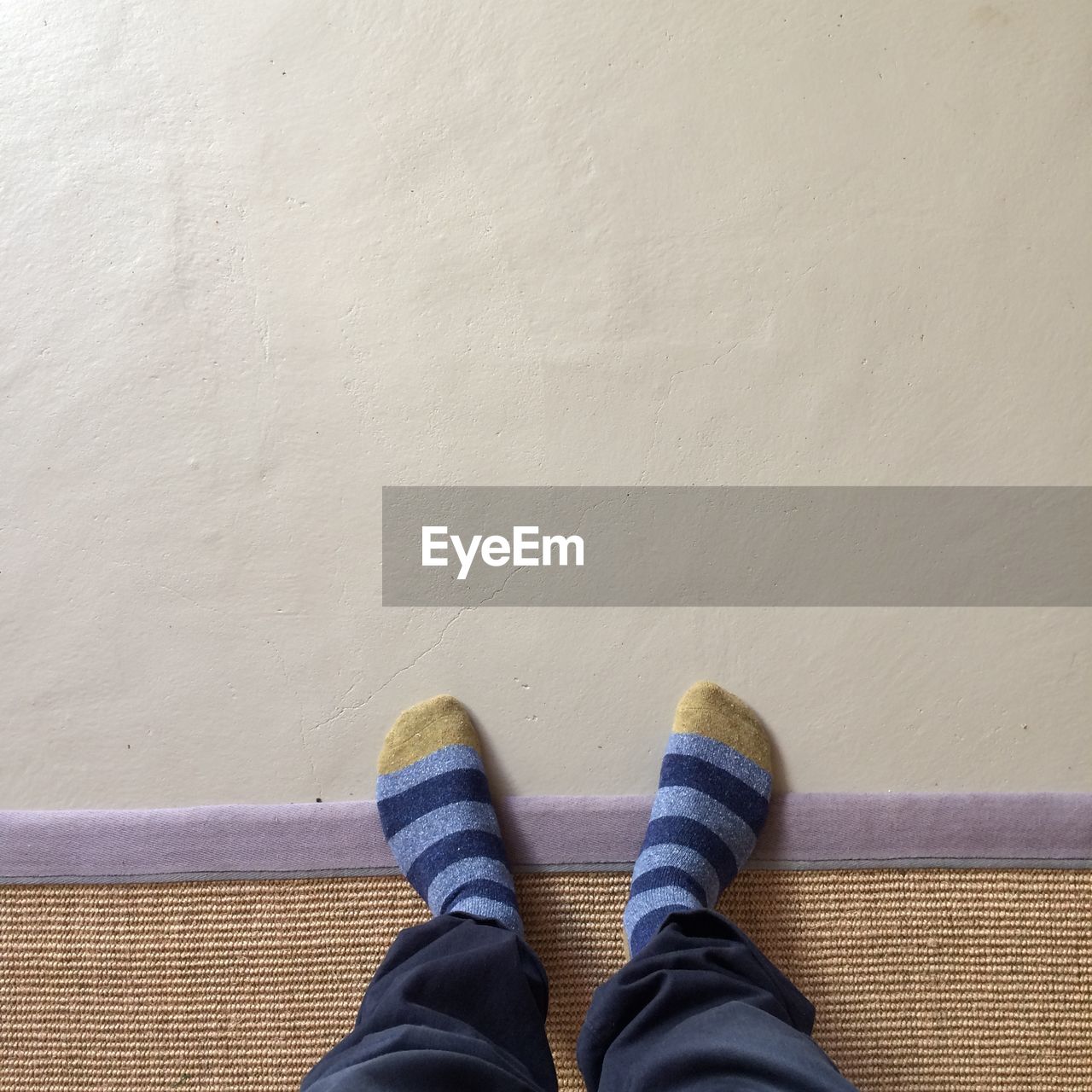 Low section of man wearing socks with feet up on wall