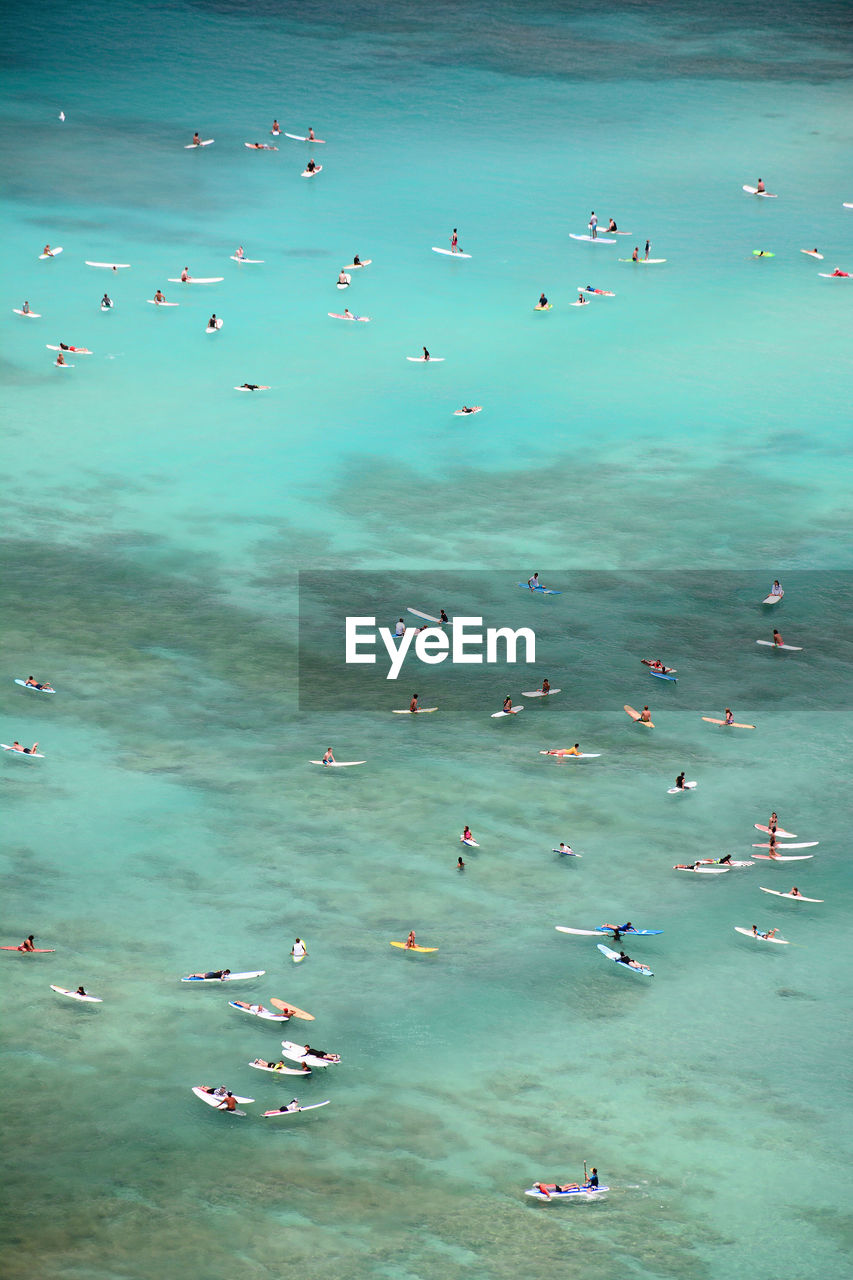 High angle view of surfers catching waves in the turquoise waters of waikiki beach on oahu, hawaii.