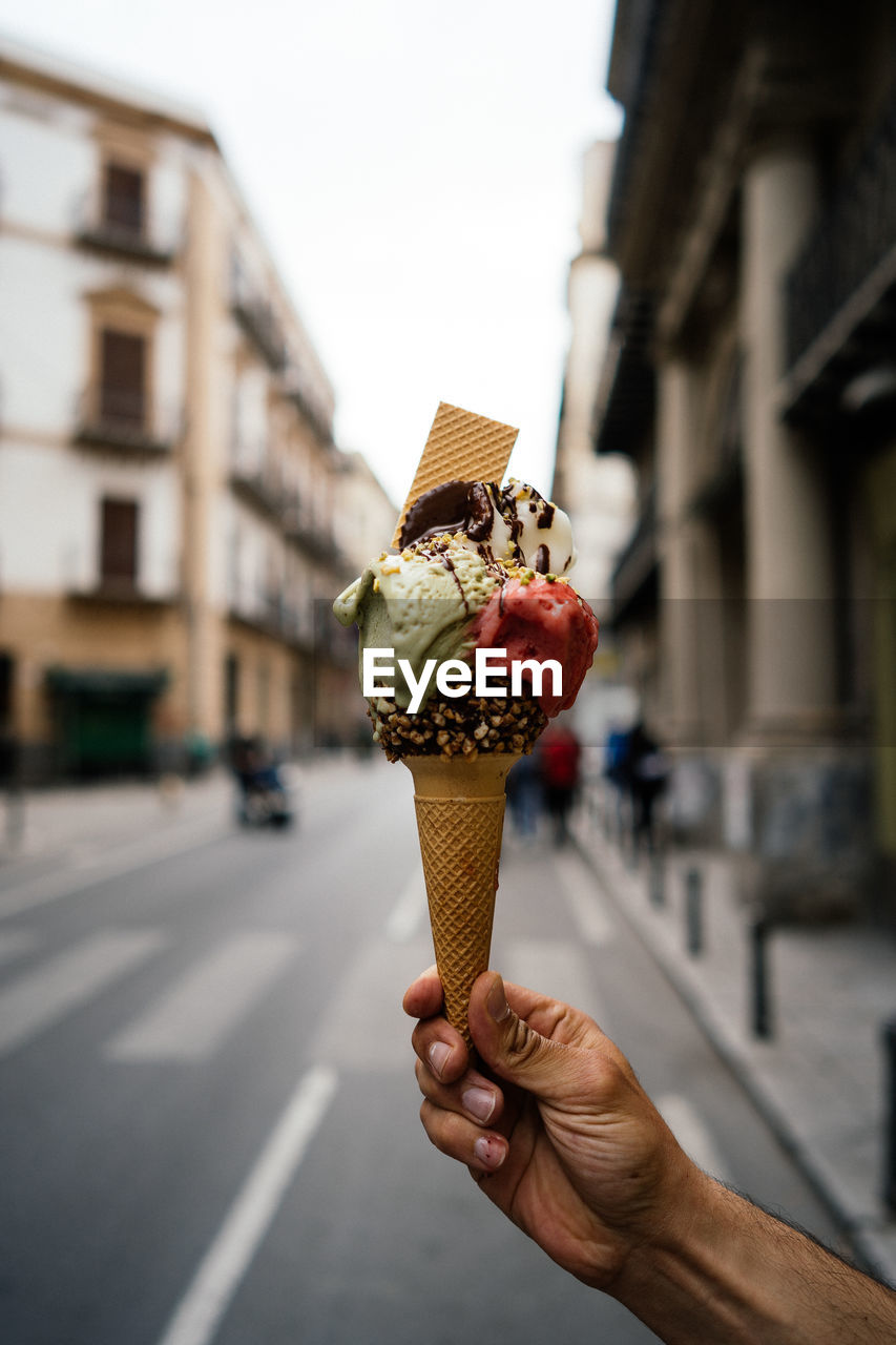 PERSON HOLDING ICE CREAM CONE ON GLASS