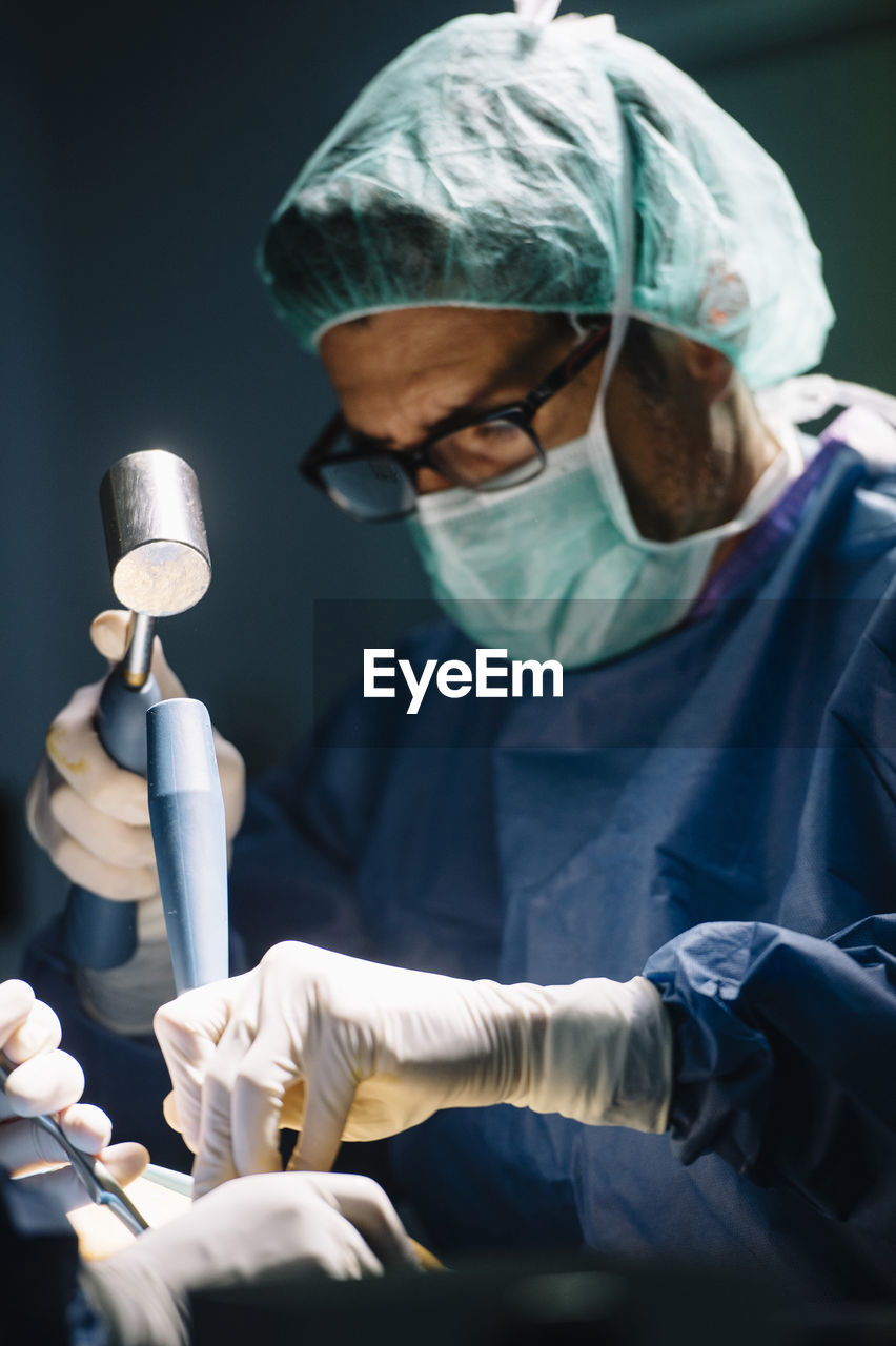 Male surgeon using hammer while doing ankle surgery in operating room