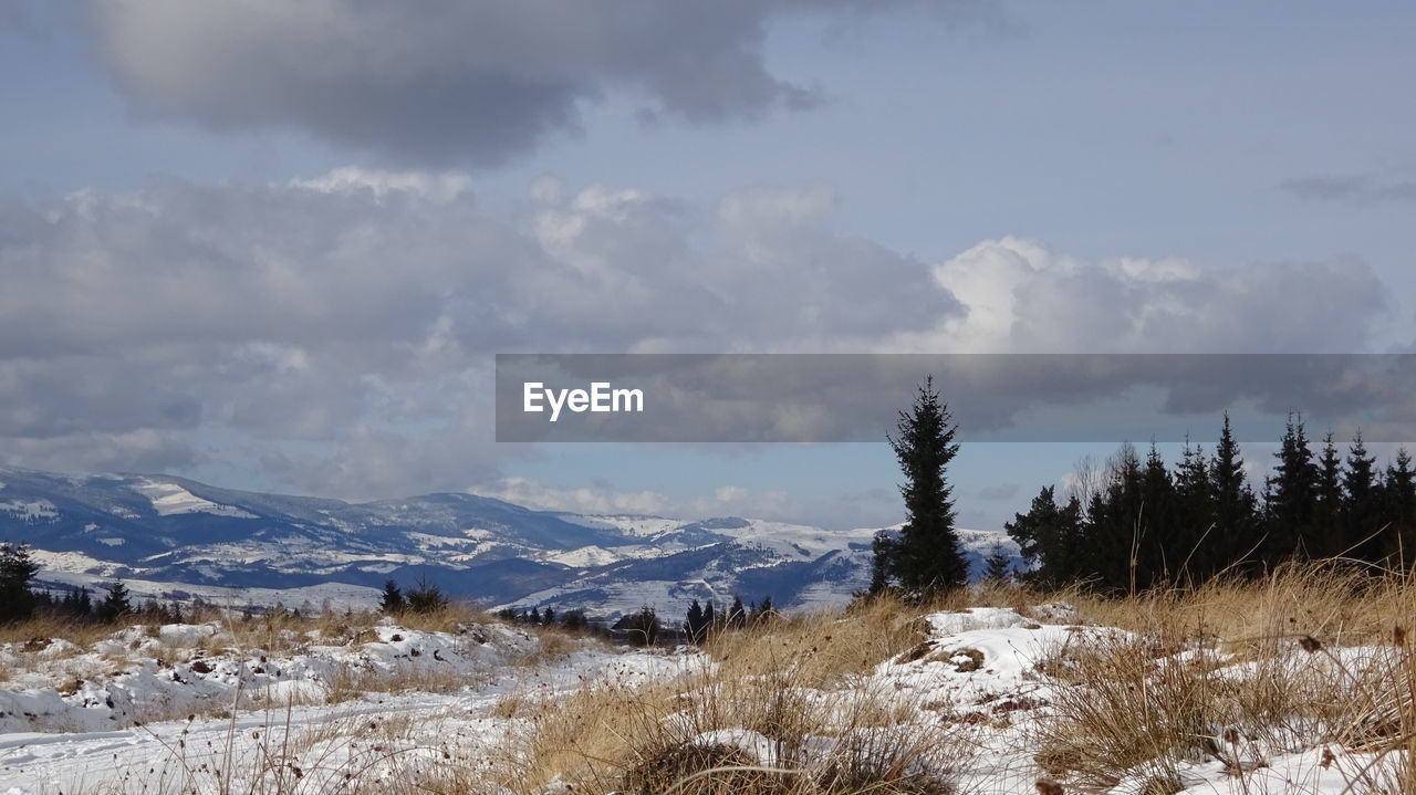 Scenic view of mountain range against cloudy sky