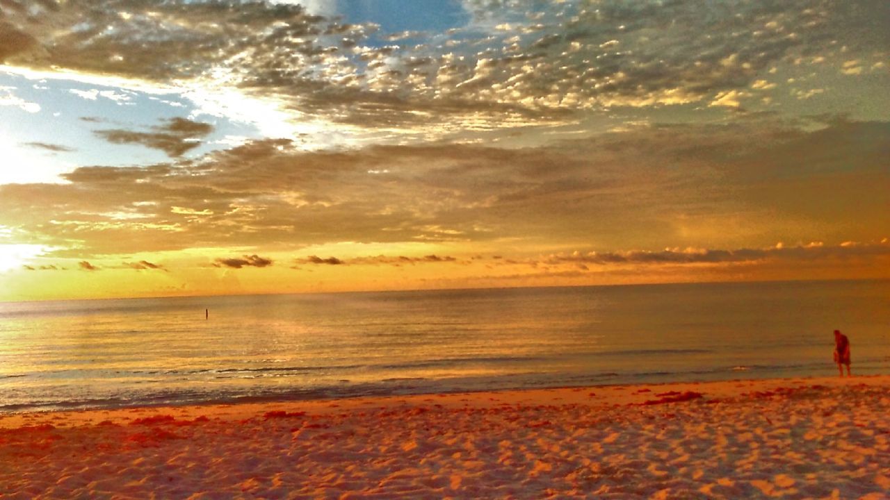 SILHOUETTE OF PEOPLE ON BEACH AT SUNSET