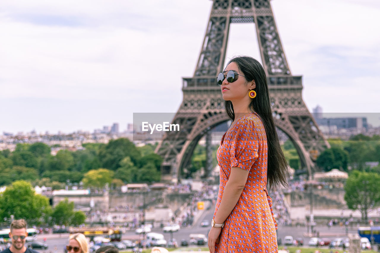 Side view of woman standing against eiffel tower