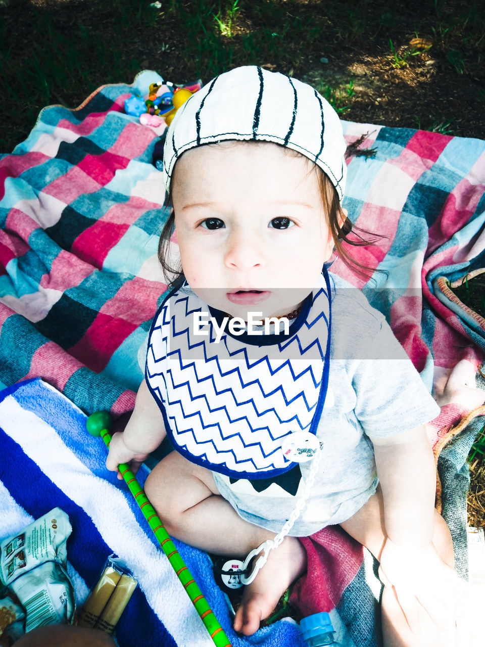 High angle portrait of cute baby boy sitting on blanket at park
