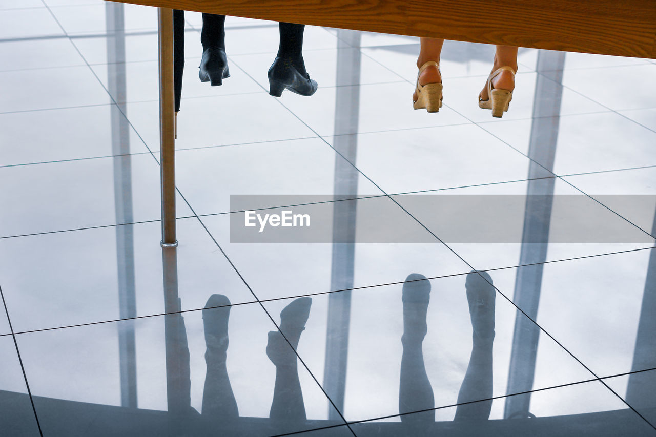 Low section of woman reflecting on tiled floor