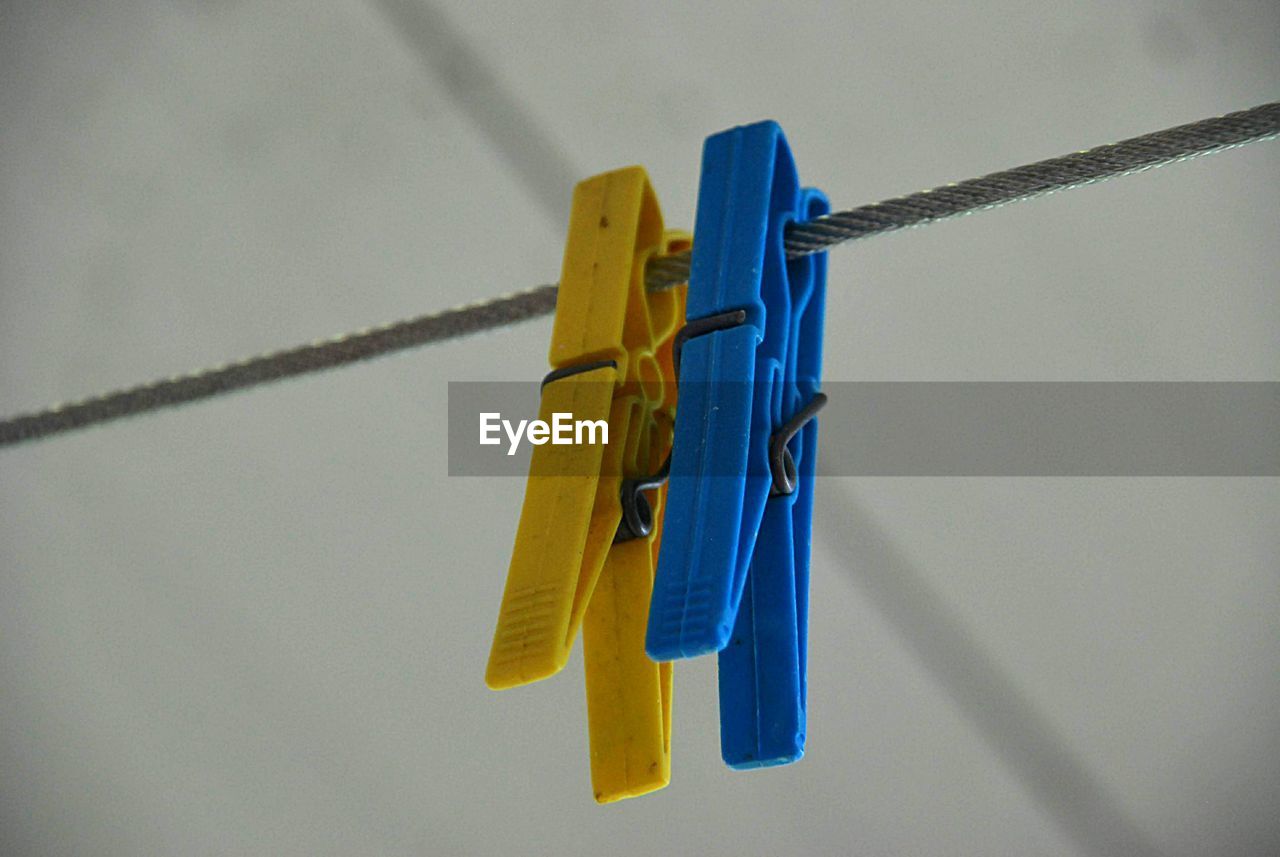 Close-up of clothespins hanging on rope against wall