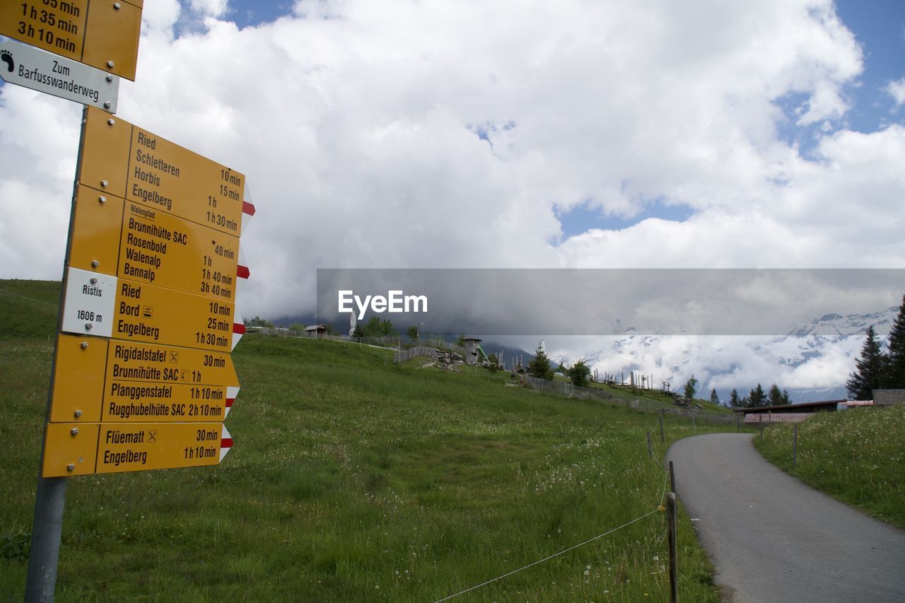 INFORMATION SIGN ON ROAD AMIDST FIELD