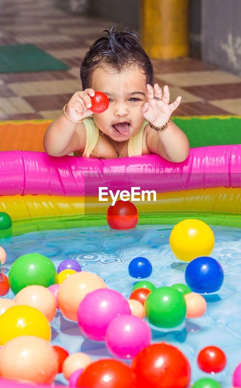 Portrait of smiling girl with colorful balls in wading pool