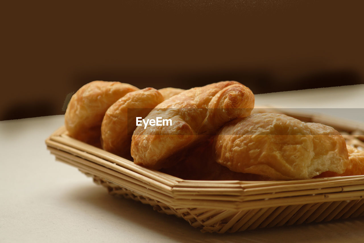 Close-up of baked breads in straw tray on table