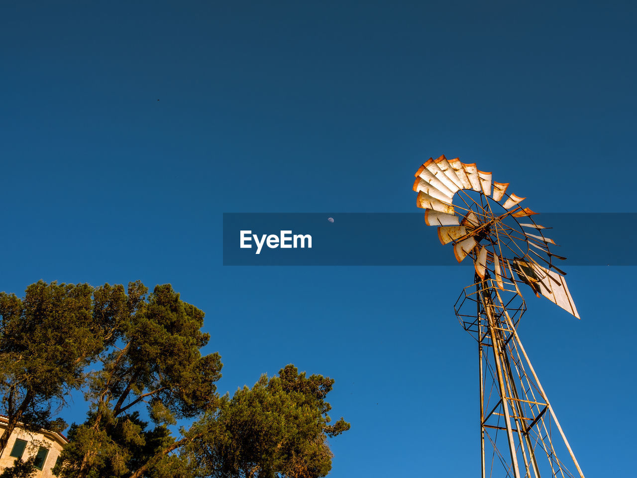 Low angle view of windmill against clear blue sky