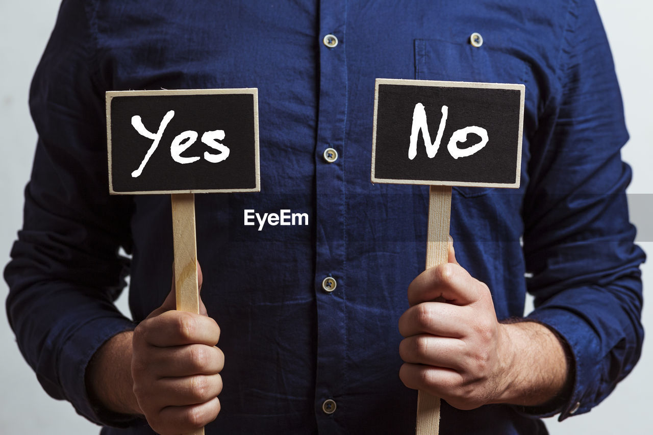 Man holding two chalkboards with yes and no  - yes and no - evaluation and decision making concept