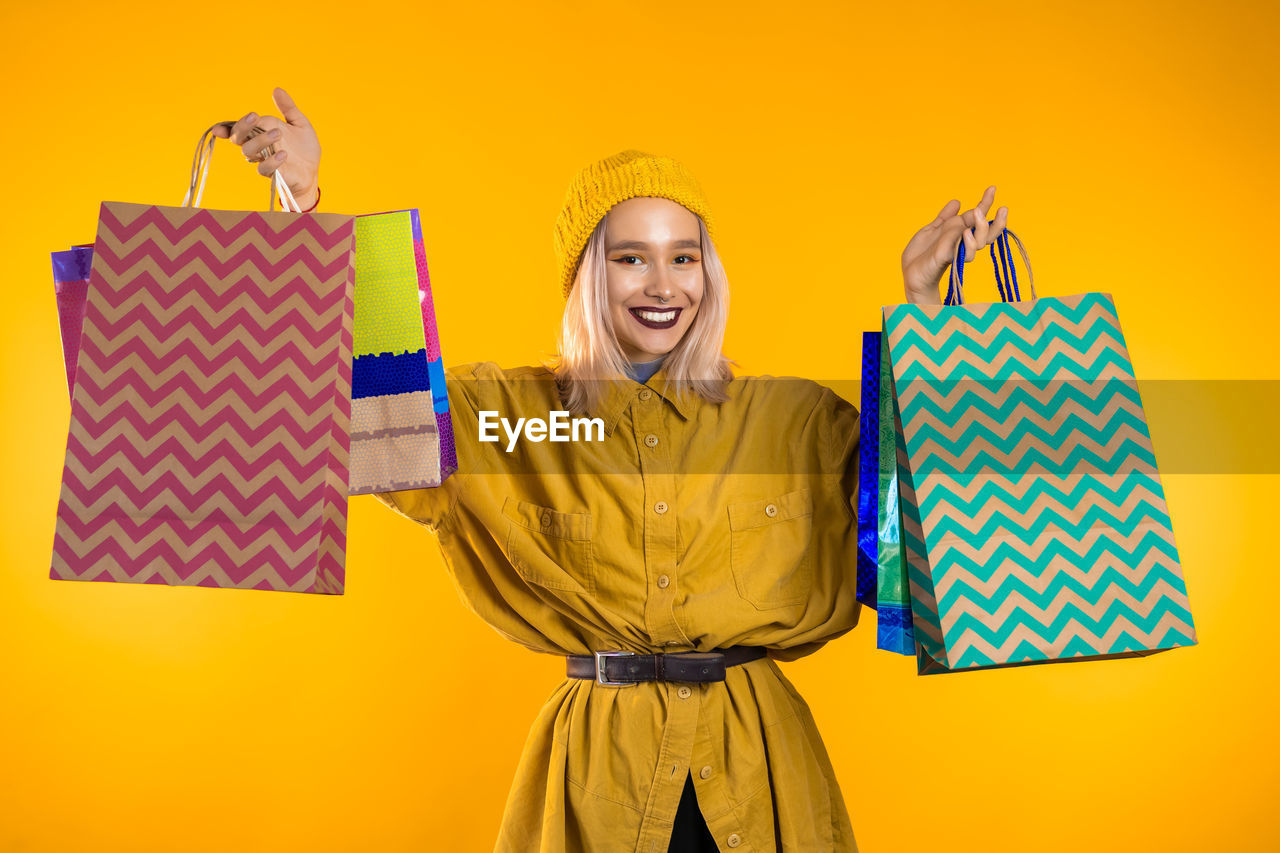 PORTRAIT OF A SMILING YOUNG WOMAN AGAINST YELLOW COLORED BACKGROUND