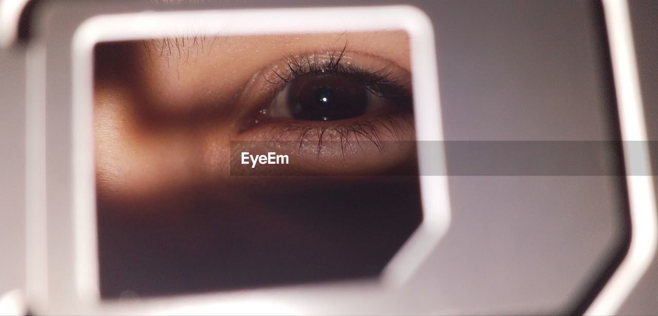 Close-up portrait of woman seen through hole in metal